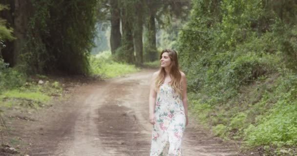 Jonge mooie vrouw met een witte jurk wandelen in een groen bos — Stockvideo