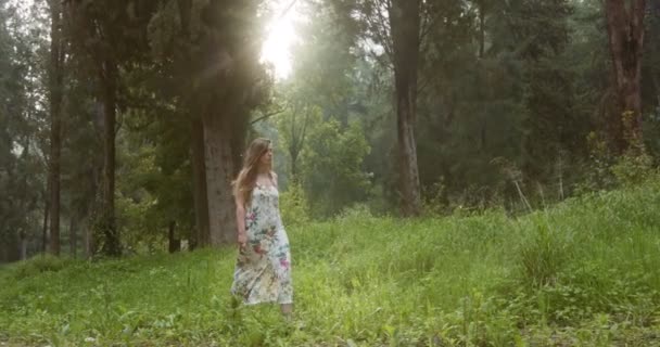 Ung vacker kvinna med en vit klänning som går i en grön skog — Stockvideo