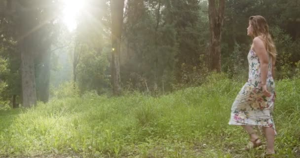 Joven hermosa mujer con un vestido blanco caminando en un bosque verde — Vídeos de Stock