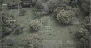 Hud grafikli bir ormanda yürüyen askerlerin gözetleme drone görünümü