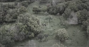 Hud grafikli bir ormanda yürüyen askerlerin gözetleme drone görünümü
