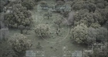Hud grafikli bir ormanda yürüyen askerlerin gözetleme drone görünümü