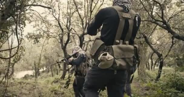Squad of armed terrorists patrolling a forest area during combat — Stock Video