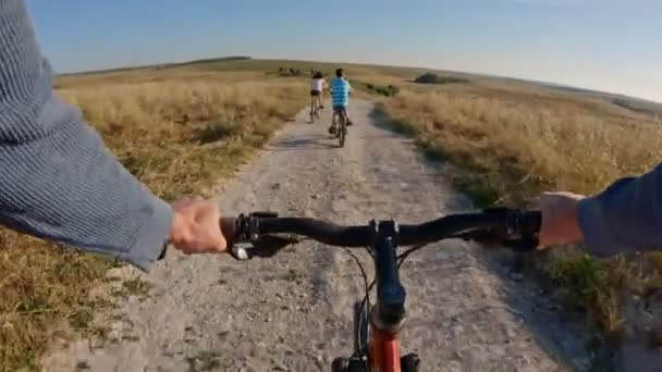 POV de duas crianças desfrutando de um passeio de bicicleta no campo com seu pai — Vídeo de Stock