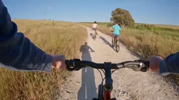 POV ze dvou dětí, které si užívají cyklistické jízdy na venkově se svým otcem — Stock video