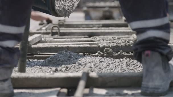 Arbeiter gießen auf einer Baustelle Beton in große Stahlformen