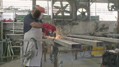 Bir işçi bir metal dükkanda uçan kıvılcımlar ile metal değirmeni kullanarak yavaş hareket