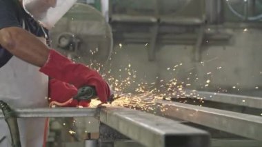 Bir işçi bir metal dükkanda uçan kıvılcımlar ile metal değirmeni kullanarak yavaş hareket