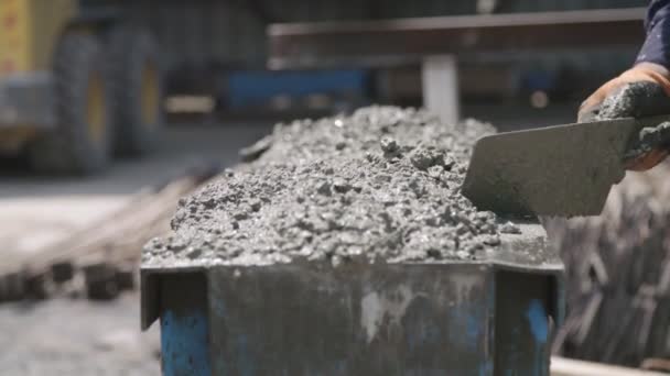 Travailleurs versant du béton dans de grands moules en acier sur un chantier de construction — Video