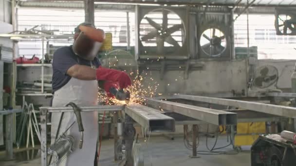Slow Motion van een werknemer met behulp van metalen grinder met vonken vliegen in een metalen winkel — Stockvideo
