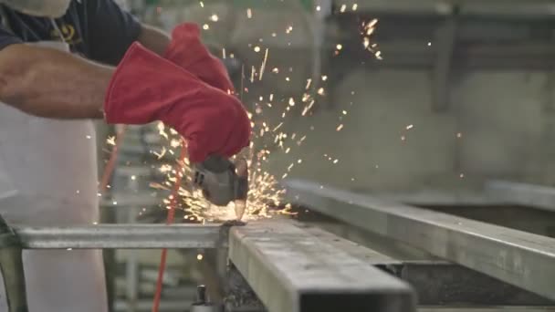 Медленное движение рабочего с помощью металлической мельницы с искрами, летящими в металлическом цехе — стоковое видео
