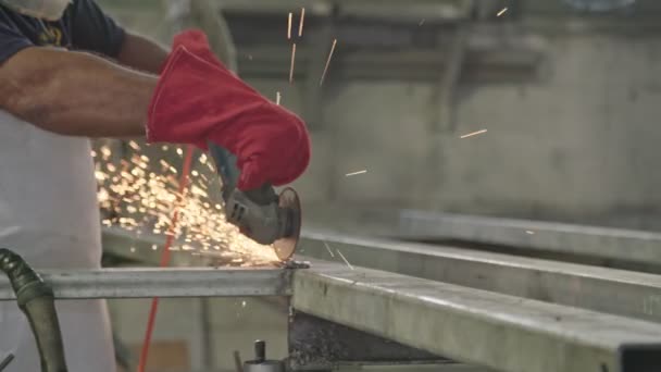 Bir işçi bir metal dükkanda uçan kıvılcımlar ile metal değirmeni kullanarak yavaş hareket — Stok video
