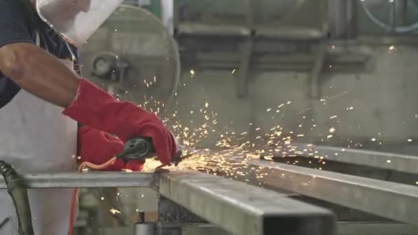 Lambat gerak seorang pekerja menggunakan penggiling logam dengan percikan api terbang di toko logam — Stok Video