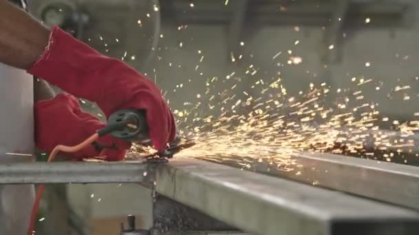 Movimiento lento de un trabajador que utiliza una amoladora de metal con chispas volando en una tienda de metal — Vídeos de Stock