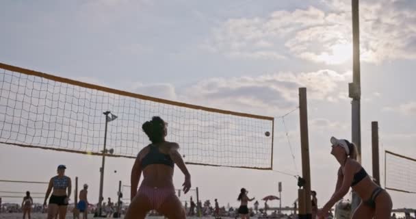 Slow Motion av kvinnor som spelar beachvolleyboll under solnedgången — Stockvideo