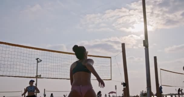 Movimiento lento de las mujeres jugando voleibol de playa durante la puesta del sol — Vídeo de stock