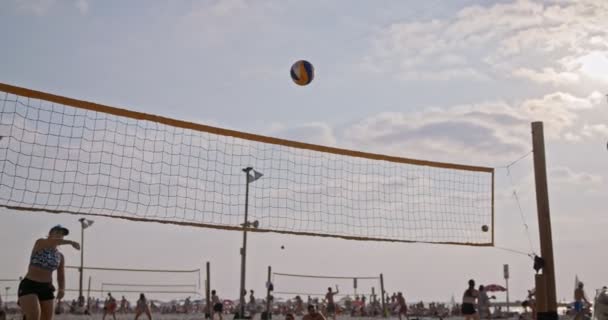 Movimiento lento de las mujeres jugando voleibol de playa durante la puesta del sol — Vídeos de Stock