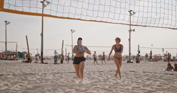 Movimiento lento de las mujeres jugando voleibol de playa durante la puesta del sol — Vídeo de stock