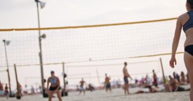 Gün batımında plaj voleybolu oynayan kadınların yavaş hareketi