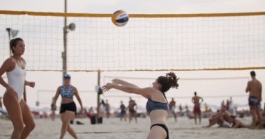 Gün batımında plaj voleybolu oynayan kadınların yavaş hareketi