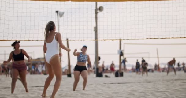 Movimiento lento de las mujeres jugando voleibol de playa durante la puesta del sol — Vídeos de Stock