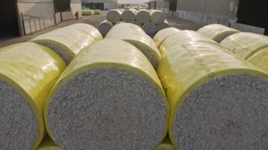 Large stacks of cotton bales at a cotton gin after harvest