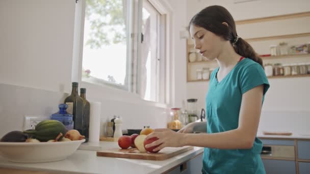 Tiener meisje werken snijden fruit voor het ontbijt in de keuken — Stockvideo