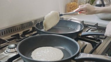 Küçük çocuklar mutfakta kızartma tavası kullanarak krep hazırlıyorlar.