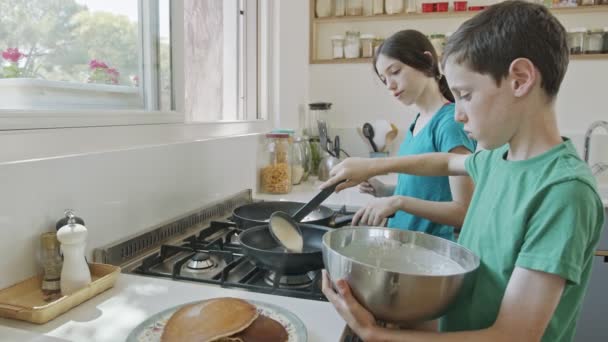 Niños pequeños preparando panqueques en la cocina usando una sartén — Vídeos de Stock