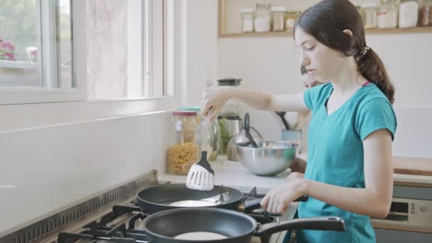 Unga barn förbereder pannkakor i köket med en stekpanna — Stockvideo