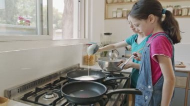 İki genç kız mutfakta tavayla krep hazırlıyor.