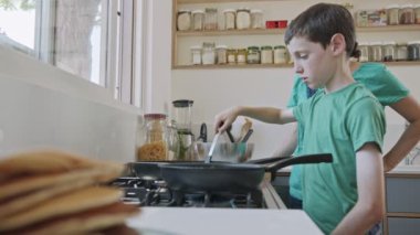 Çocuk kahvaltıya annesiyle birlikte mutfakta krep hazırlıyor.