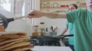 Çocuk kahvaltıya annesiyle birlikte mutfakta krep hazırlıyor.