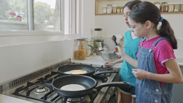 주방에서 프라이팬을 사용하여 팬케이크를 만드는 두 소녀 — 비디오