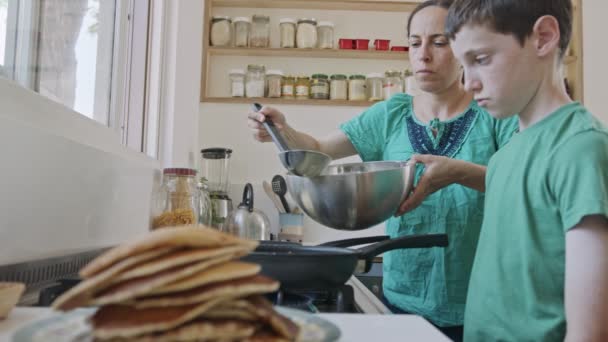 Pojken förbereder pannkakor med sin mamma till frukost i köket — Stockvideo