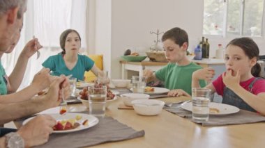 Üç çocuk anne babalarıyla krep ve meyve kahvaltısı yapıyor.