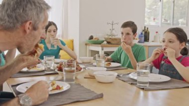 Üç çocuk anne babalarıyla krep ve meyve kahvaltısı yapıyor.