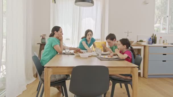 Moeder en drie kinderen ontbijten van pannenkoeken en fruit — Stockvideo