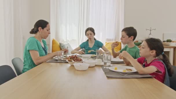 Mãe e três crianças tomando café da manhã de panquecas e frutas — Vídeo de Stock