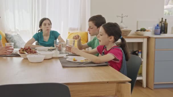 Mãe e três crianças tomando café da manhã de panquecas e frutas — Vídeo de Stock