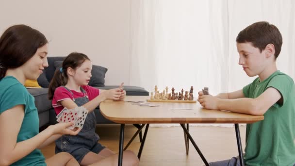 Trójka dzieciaków gra w szaloną grę w salonie, krzycząc i kłócąc się — Wideo stockowe