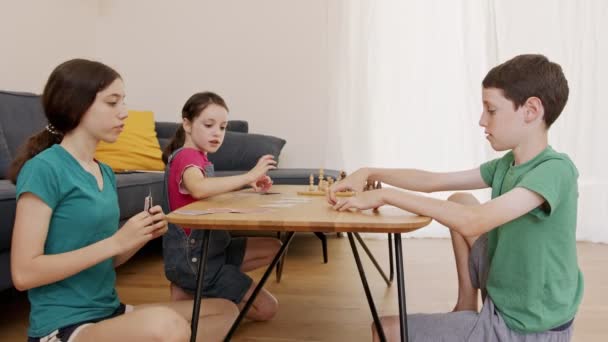 Трое детей играют в игру в гостиной, кричат и спорят — стоковое видео