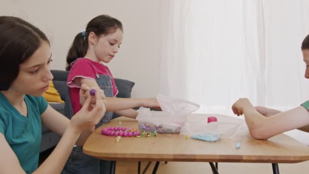 Barn upptagen med att skapa konstverk med pärlor gängade på strängar — Stockvideo