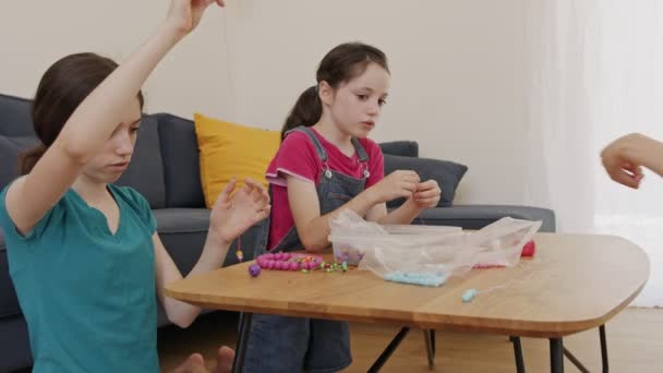 Kinder basteln Kunstwerke mit Perlen, die auf Fäden aufgefädelt sind — Stockvideo