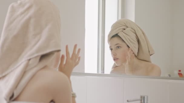 Teenagermädchen schaut im Badezimmer in den Spiegel - überprüft ihr Gesicht — Stockvideo