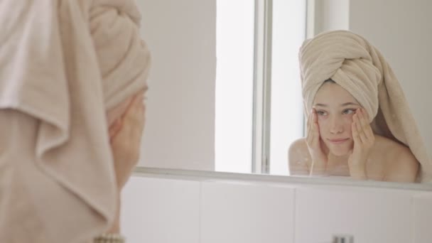 Teenage dívka dívá na zrcadlo v koupelně - kontrola její obličej — Stock video