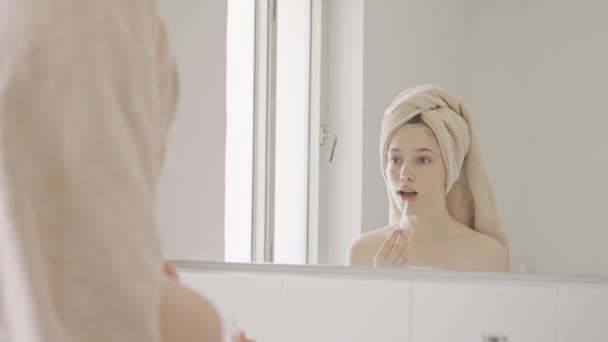 Tonårstjej som applicerar läppbalsam och läppglans framför badrumsspegeln — Stockvideo