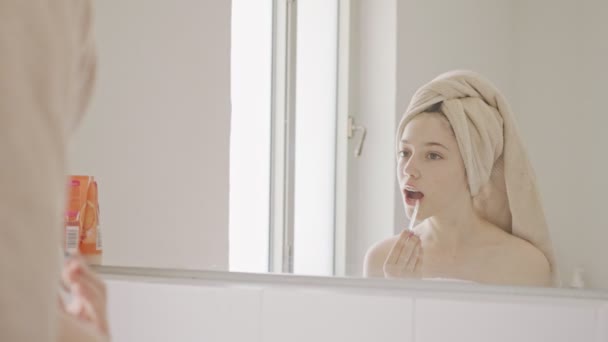 Teenage girl applying lip balm and lip gloss in front of the bathroom mirror — Stock Video