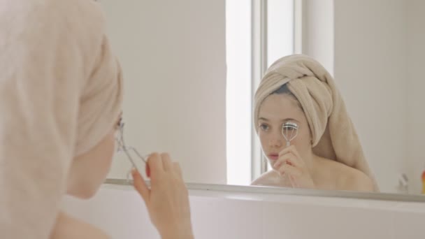 Adolescente à l'aide d'un friseur de cils devant le miroir de salle de bains — Video