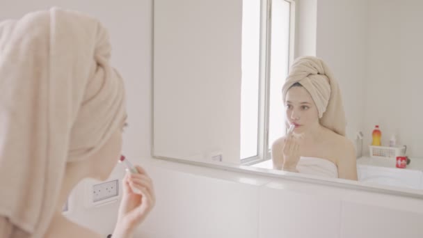 Teenage girl applying makeup in front of the bathroom mirror — Stock Video